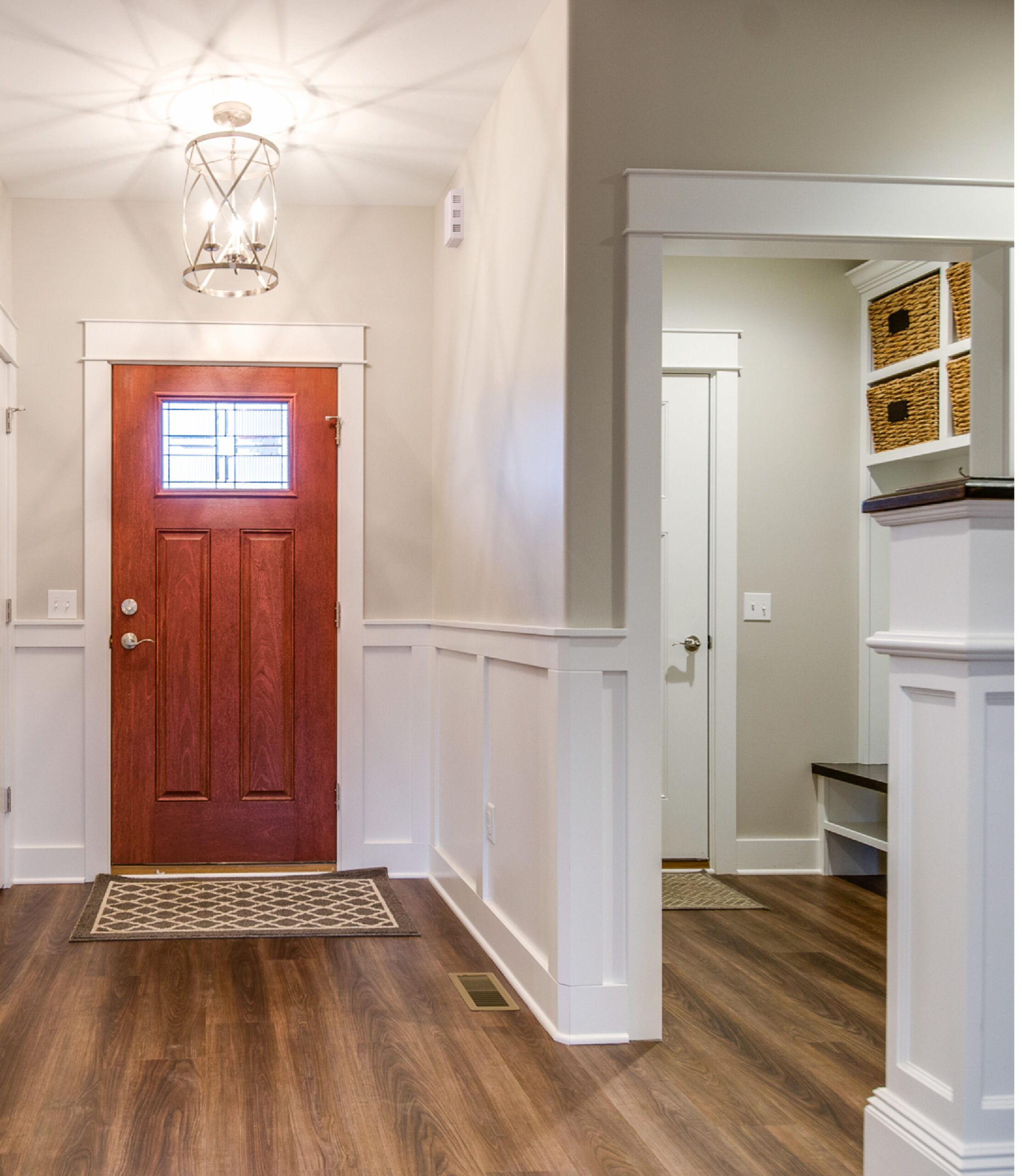 Home remodel of modern mudroom entry with sliding barn door, built-in bench and hooks, and durable wood-look flooring